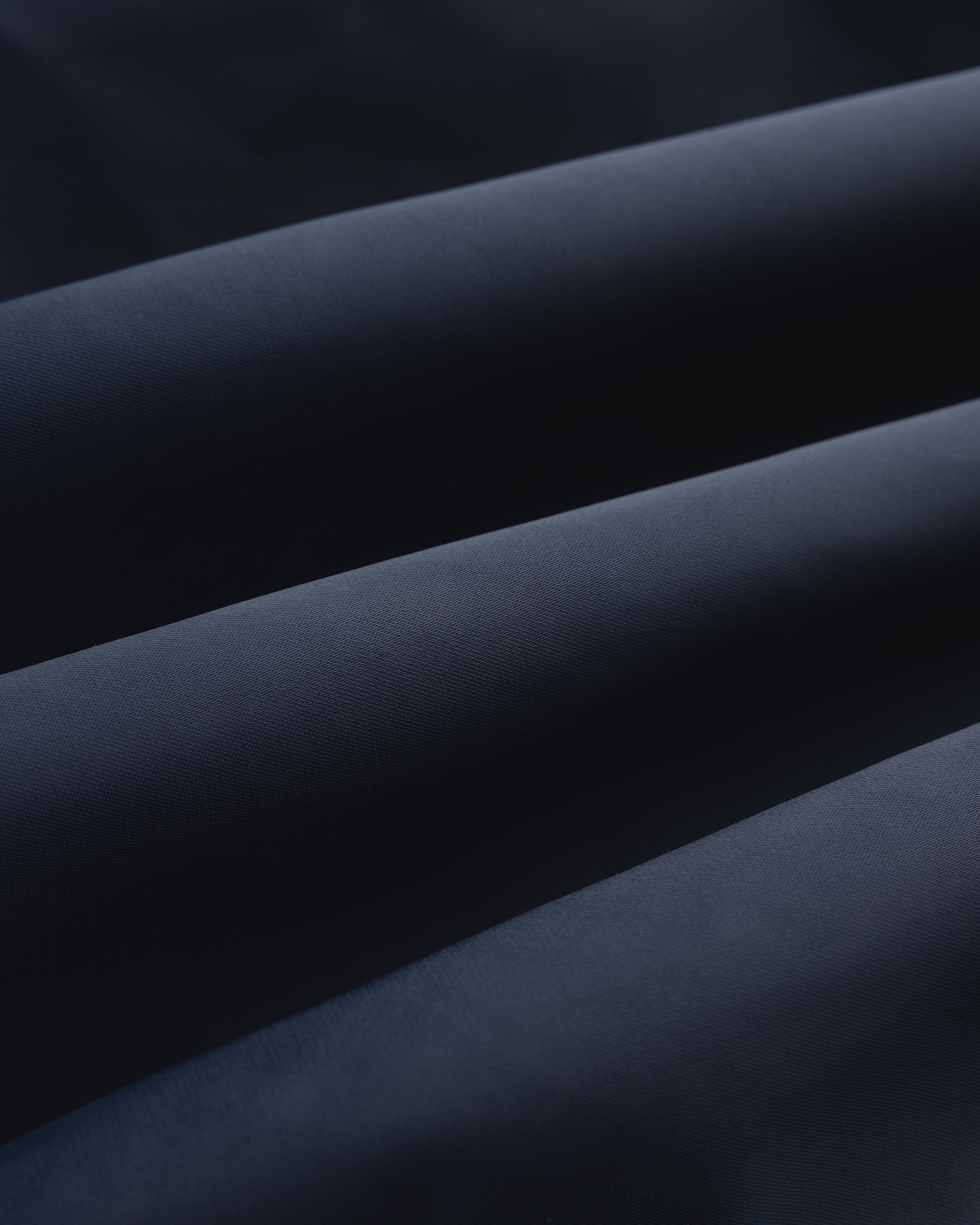 Close-up of folded Overlay Logo Satin Varsity Jacket in dark blue with a soft, smooth texture and gentle shadows.