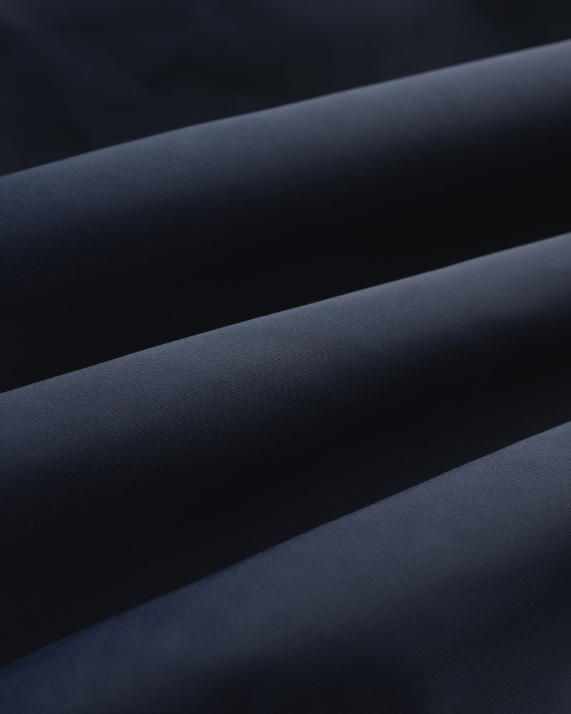 Close-up of folded Overlay Logo Satin Varsity Jacket in dark blue with a soft, smooth texture and gentle shadows.