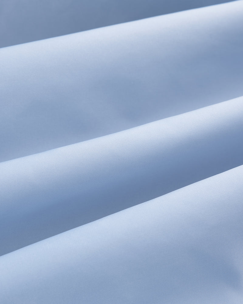 Close-up of smooth, light blue Overlay Logo Satin Varsity Jacket fabric with soft parallel diagonal folds.