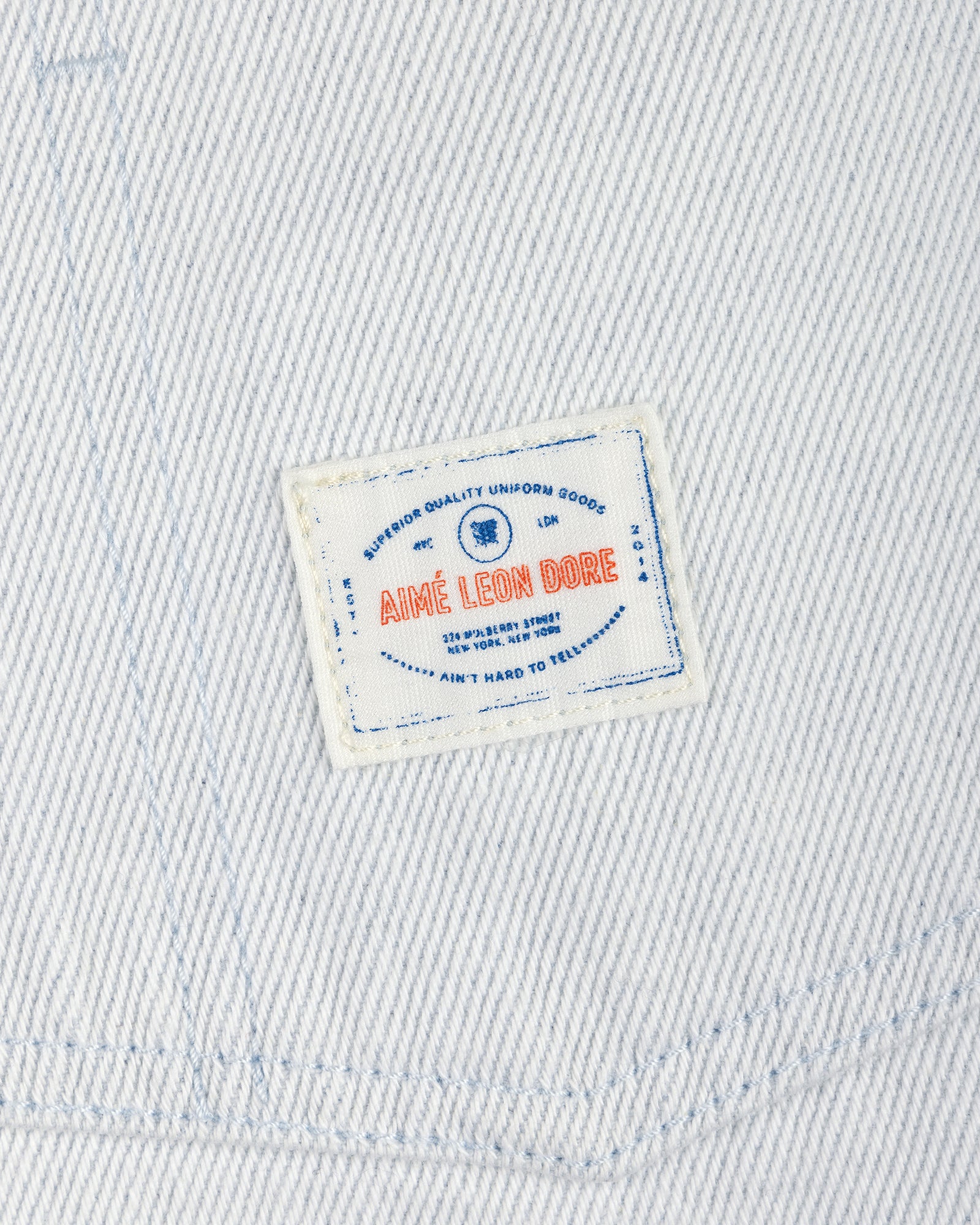 White Denim Barn Jacket with a small rectangular patch reading AIMÉ LEON DORE in red and blue text.