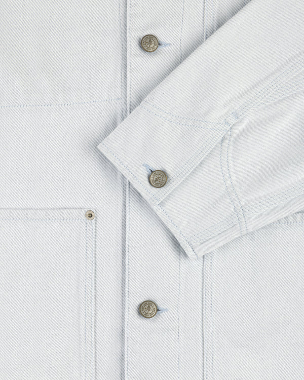 Close-up of the Denim Barn Jacket in light blue, showing metal buttons, front pocket, and folded sleeve.