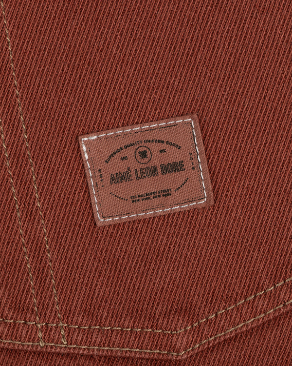 Close-up of brown fabric from the Denim Barn Jacket with a stitched Aimé Leon Dore label and white stitching.