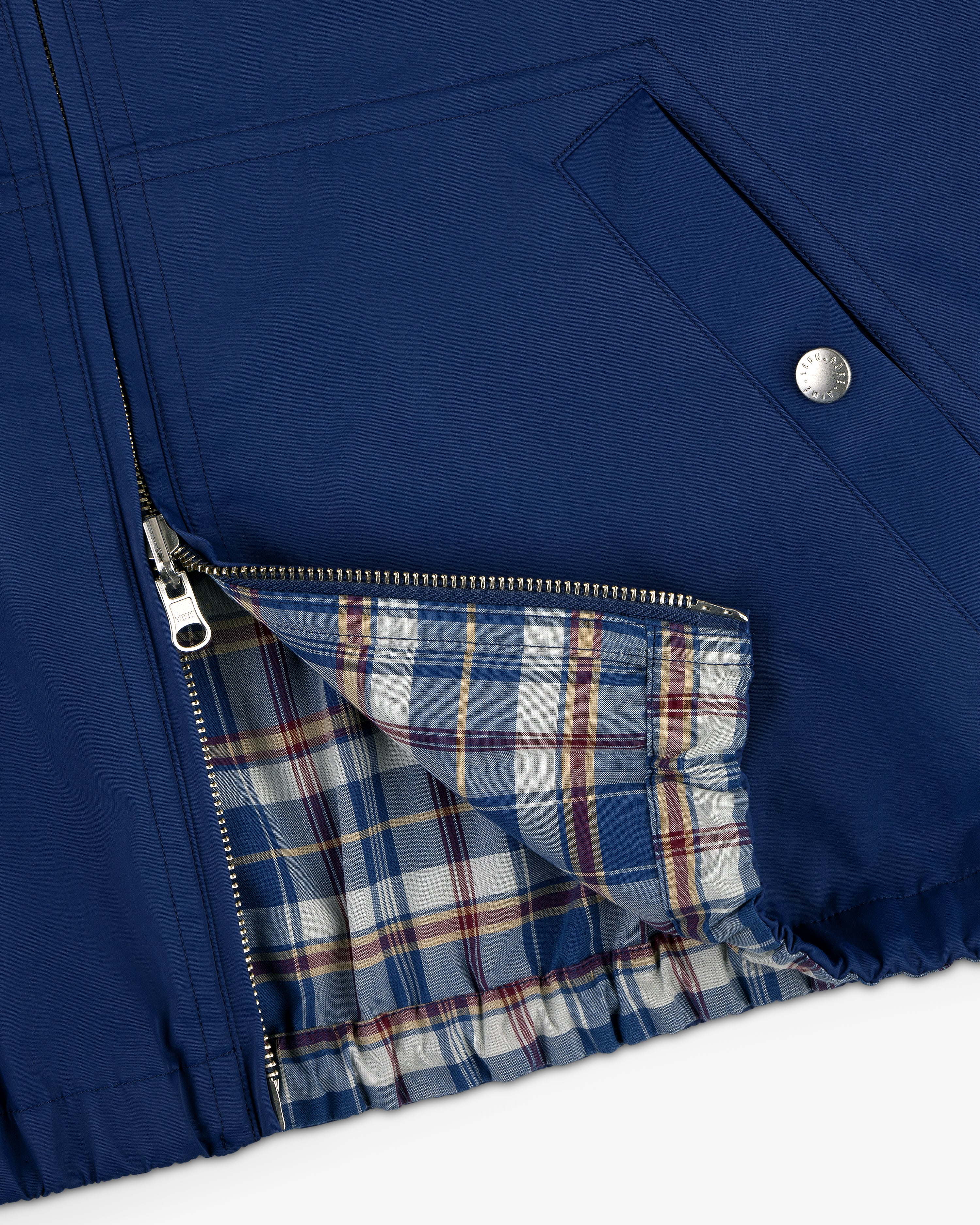 Close-up of Reversible Madras Windbreaker in blue, zipper open to reveal plaid lining and snap-button pocket.