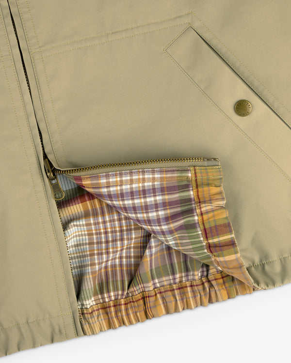 Close-up of a Reversible Madras Windbreaker in beige, featuring a zipper and colorful plaid lining inside.