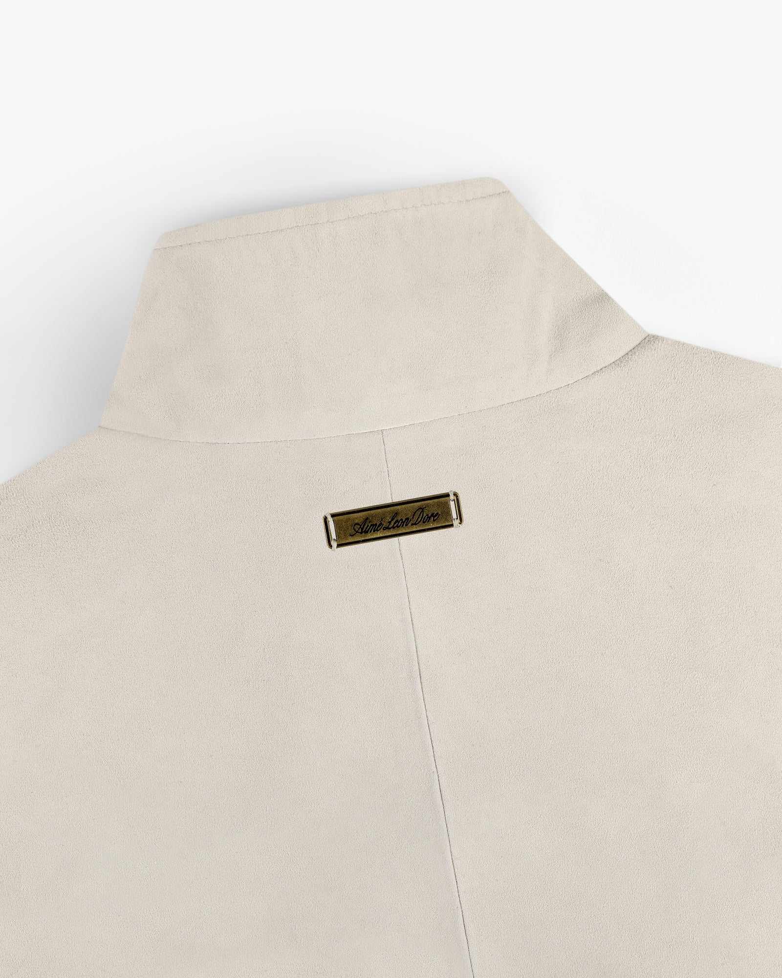 Close-up of the back collar of the Suede Track Jacket in beige with a small gold nameplate near the top center.