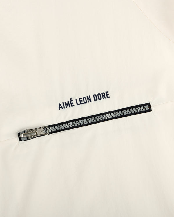 Close-up of an off-white Nylon Packable Windbreaker with a silver zipper and AIMÉ LEON DORE text above it.