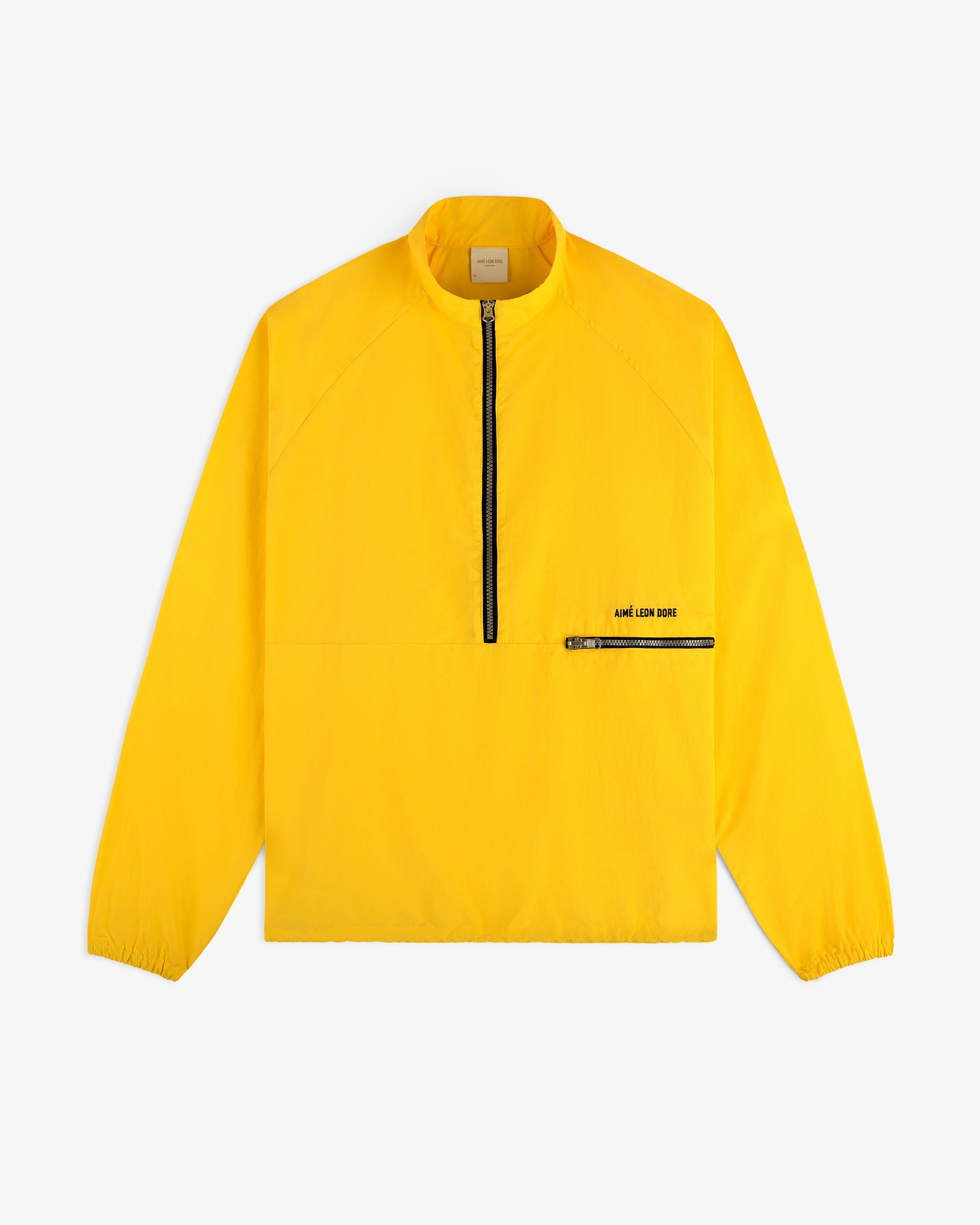 Bright yellow Nylon Packable Windbreaker with black half-zip, zip chest pocket, and AIMÉ LEON DORE branding.