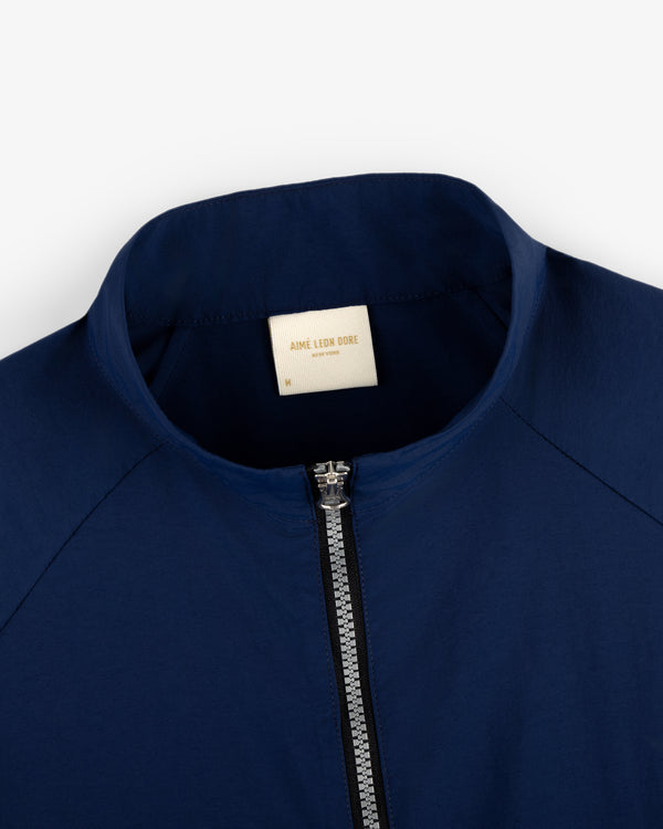 Close-up of a navy blue Nylon Packable Windbreaker with a white Aimé Leon Dore label inside the collar.