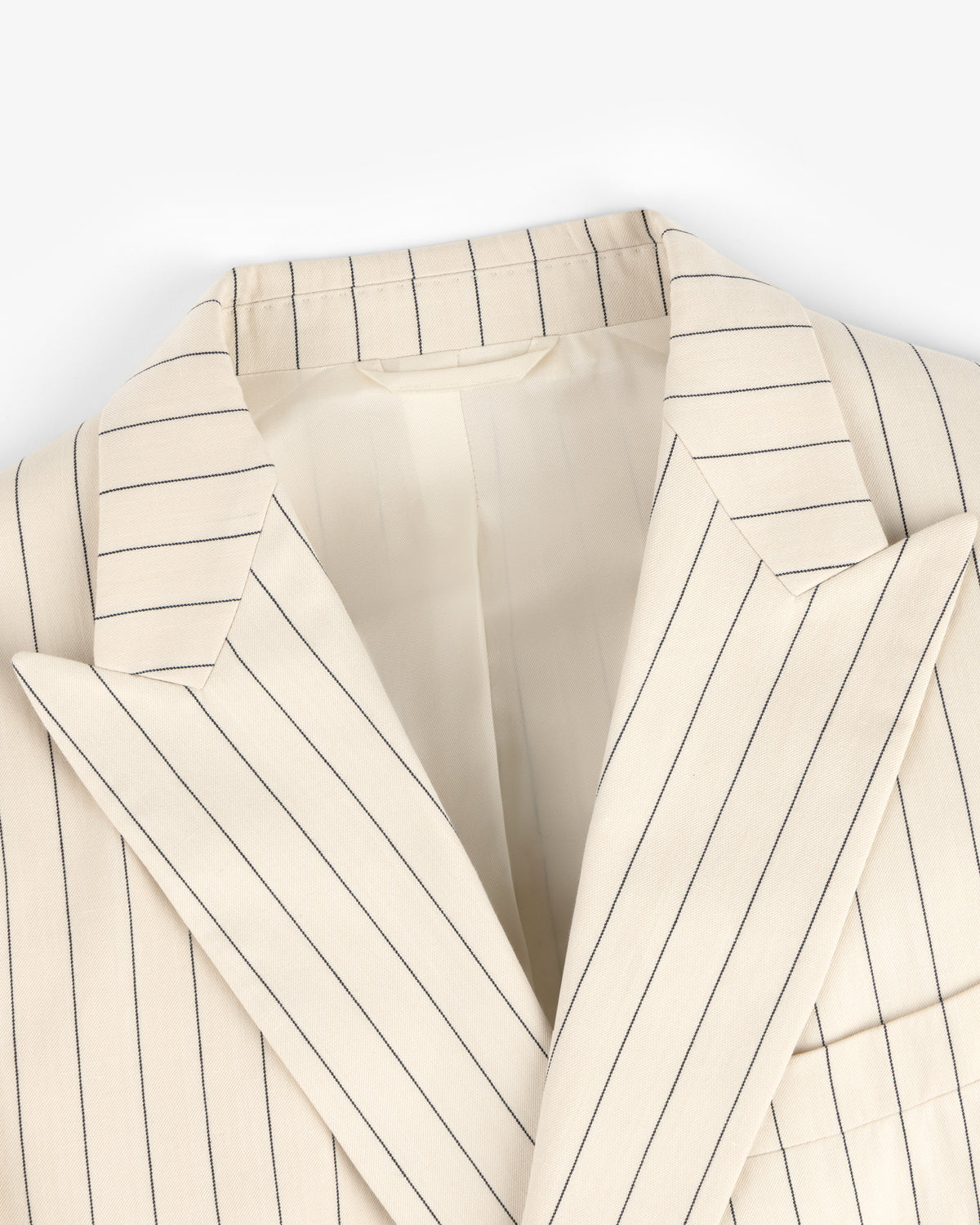 Close-up of a Double-Breasted Pinstripe Suit Jacket in cream with thin navy stripes and wide lapels.