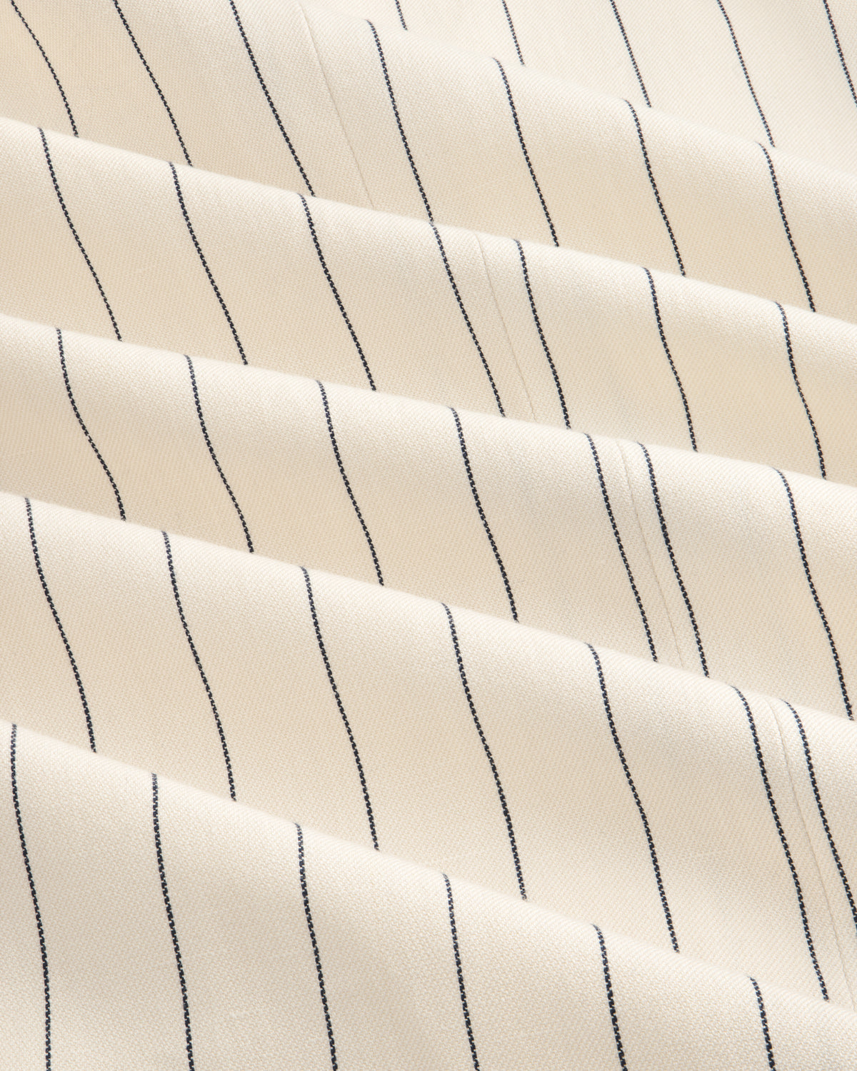 Close-up of Double-Breasted Pinstripe Suit Jacket in cream with evenly spaced thin black vertical stripes.