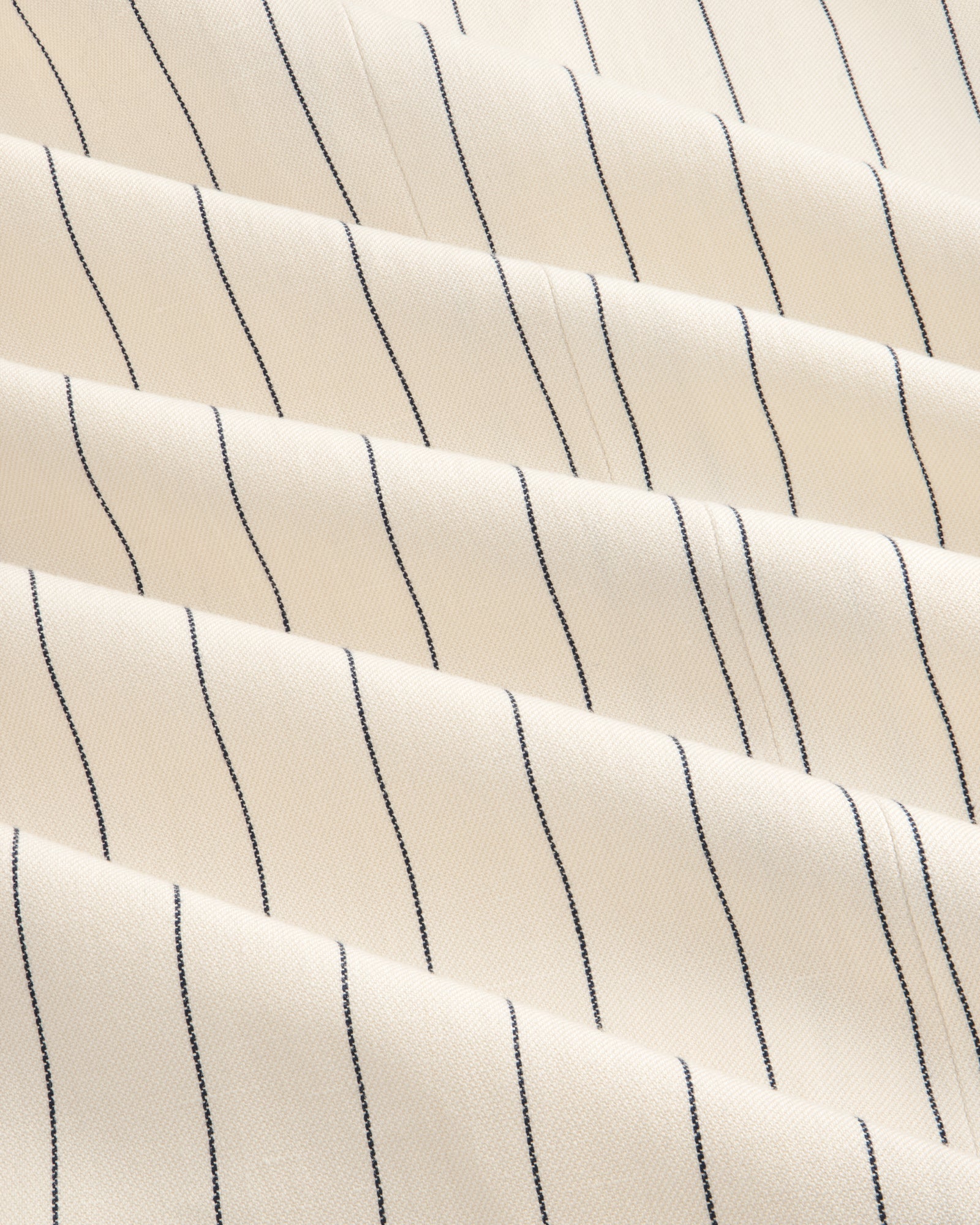 Close-up of Double-Breasted Pinstripe Suit Jacket in cream with evenly spaced thin black vertical stripes.