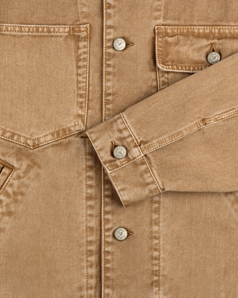 Close-up of a Denim Trucker Jacket with front pockets, silver buttons, and a folded sleeve.