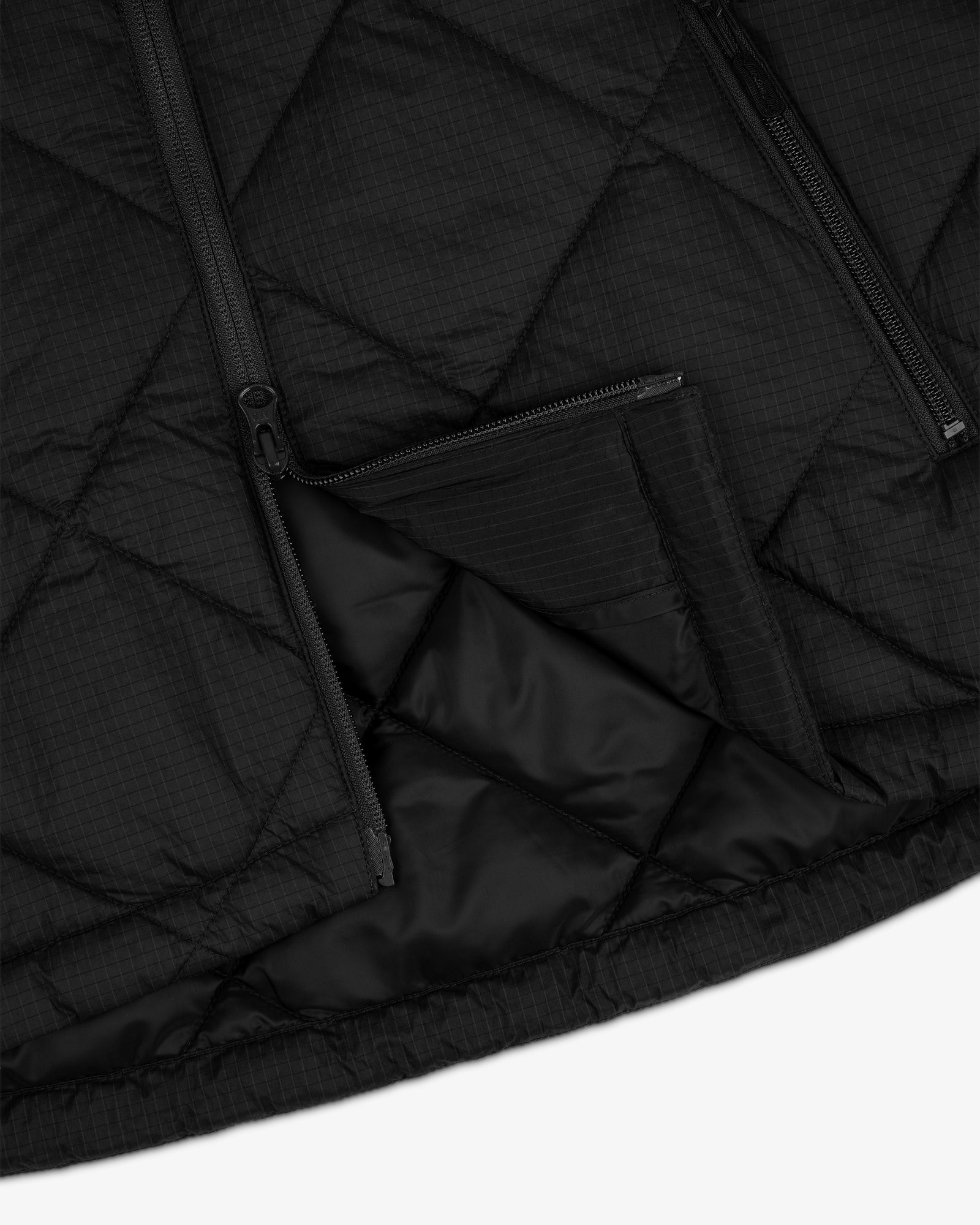 Close-up of the black Nylon Quilted Unisphere Jacket featuring diagonal stitching and two unzipped pockets.