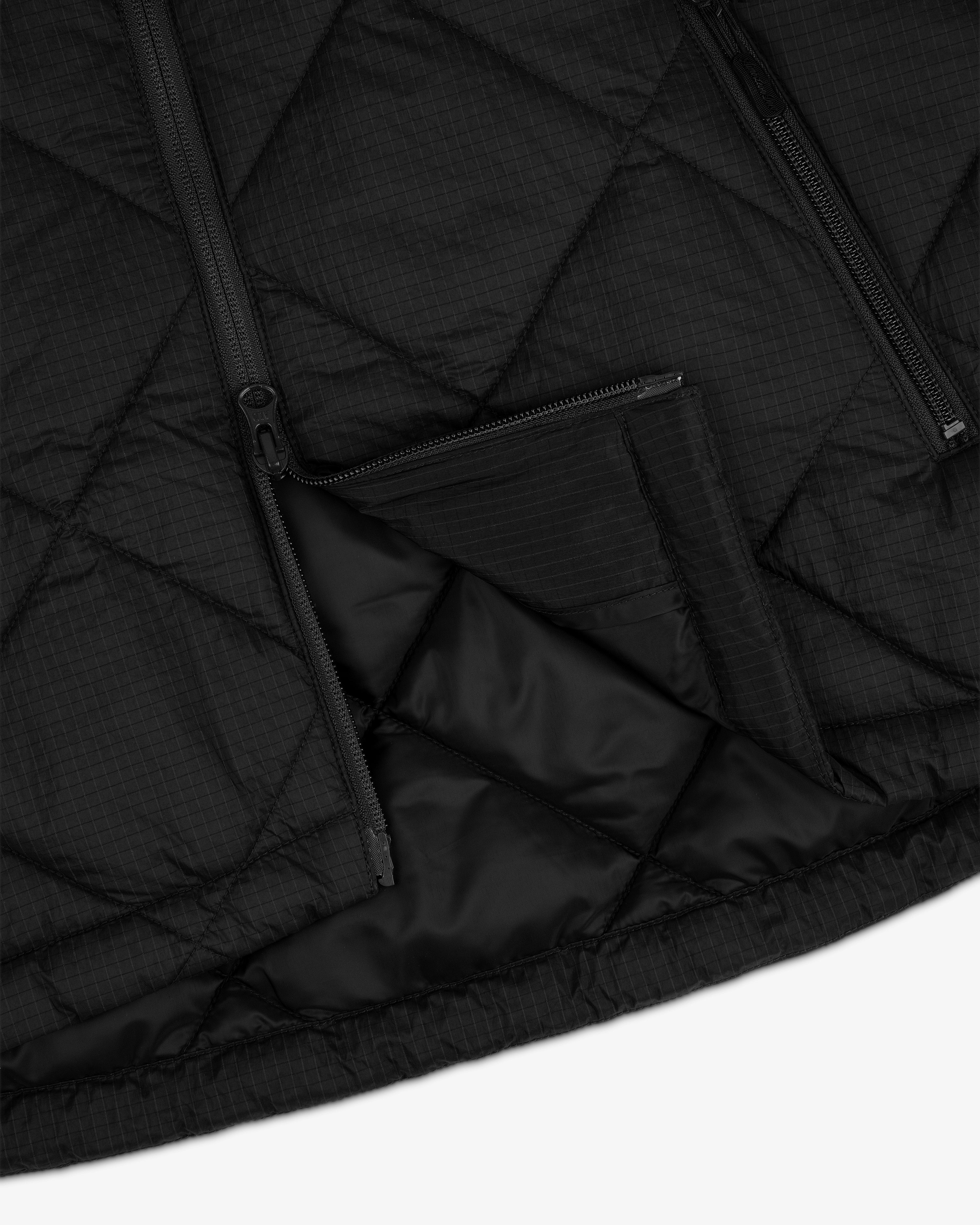 Close-up of the black Nylon Quilted Unisphere Jacket featuring diagonal stitching and two unzipped pockets.