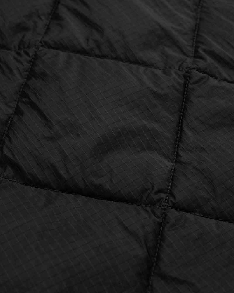 Close-up of the Nylon Quilted Unisphere Jacket's black quilted fabric with visible stitching and a subtle grid pattern.