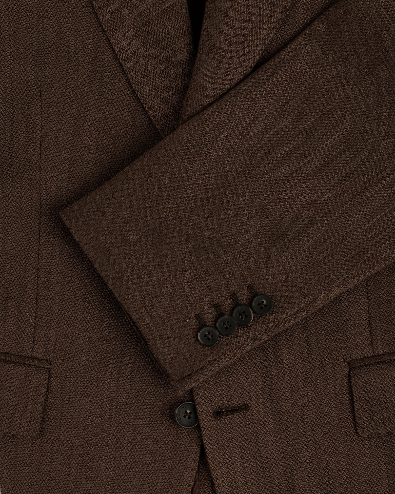 Close-up of the Single-Breasted Linen Blend Suit Jacket’s brown sleeve with four black buttons and two front pockets.