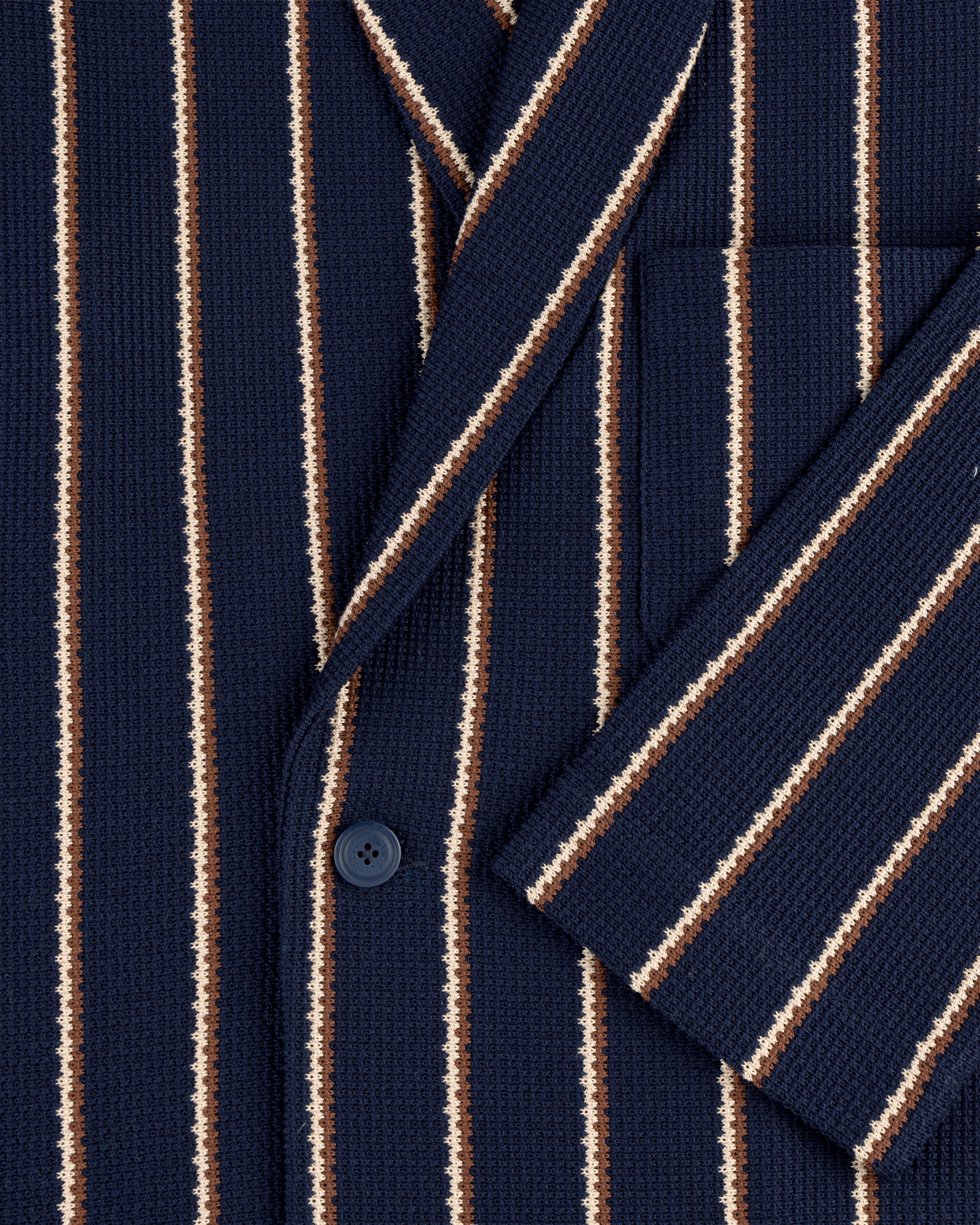 Close-up of Striped Jacquard Shawl Collar Jacket in navy with vertical white, brown, and tan stripes, button, and pocket.