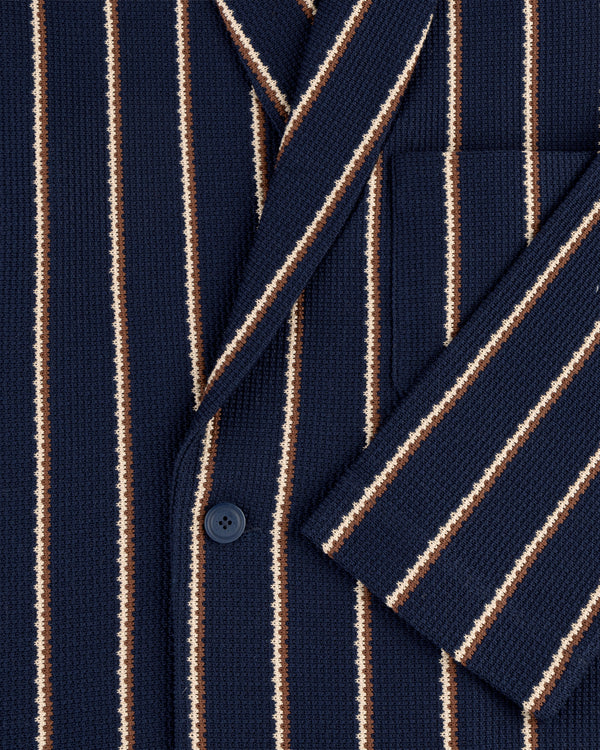 Close-up of Striped Jacquard Shawl Collar Jacket in navy with vertical white, brown, and tan stripes, button, and pocket.