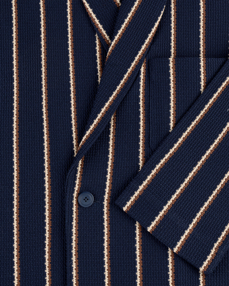 Close-up of Striped Jacquard Shawl Collar Jacket in navy with vertical white, brown, and tan stripes, button, and pocket.