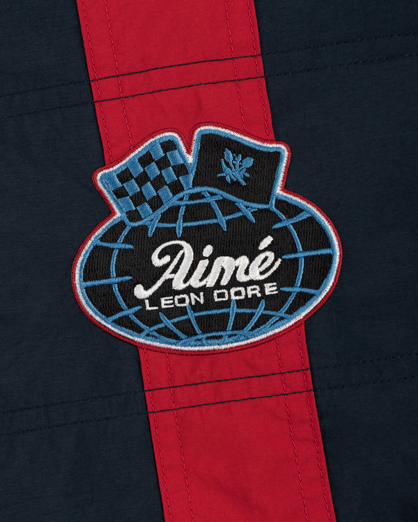 Nylon Moto Jacket in navy and red with an Aimé Leon Dore globe patch featuring a checkered flag and laurel emblem.