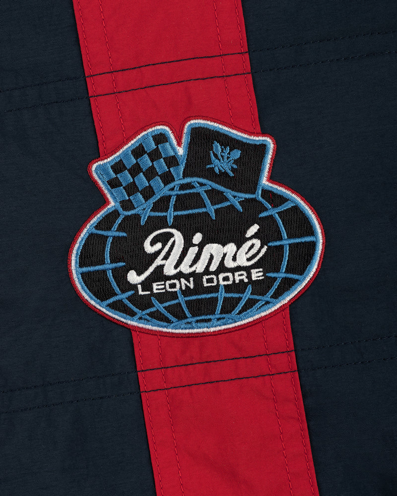 Nylon Moto Jacket in navy and red with an Aimé Leon Dore globe patch featuring a checkered flag and laurel emblem.