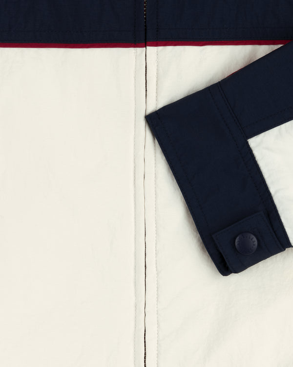 Close-up of the Nylon Moto Jacket featuring a navy sleeve and trim, white body, and thin red stripe near the top.