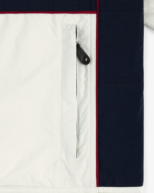 Close-up of the Nylon Moto Jacket pocket, with white fabric, a black zipper pull, and navy panel accents.