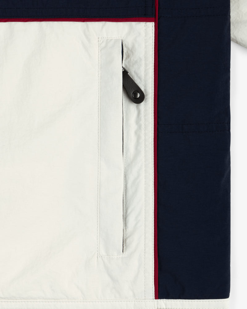 Close-up of the Nylon Moto Jacket pocket, with white fabric, a black zipper pull, and navy panel accents.