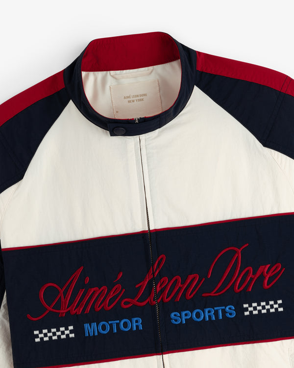 A white, navy, and red Nylon Moto Jacket with Aimé Leon Dore Motor Sports embroidered on the front.
