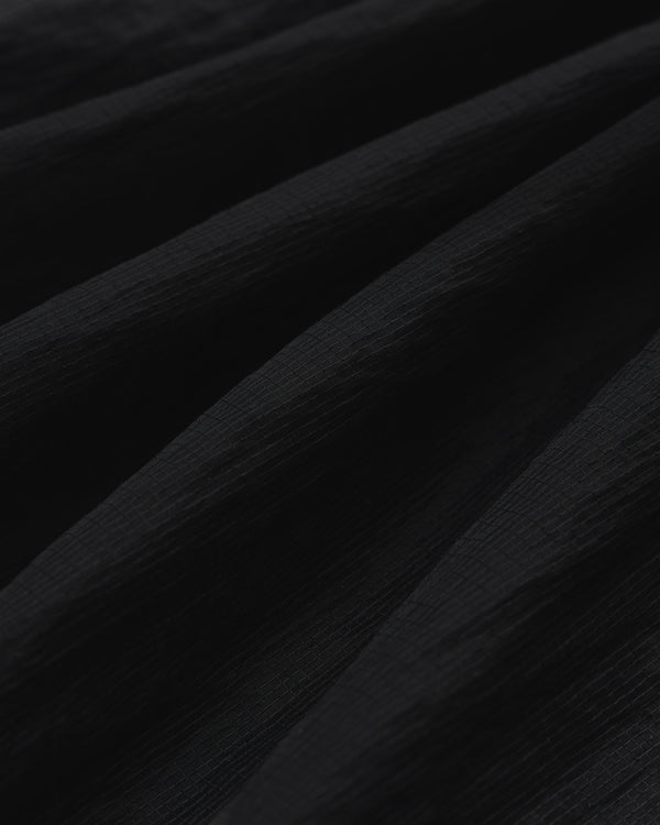 Close-up of black Nylon Track Jacket fabric with soft, diagonal folds creating shadows and depth.