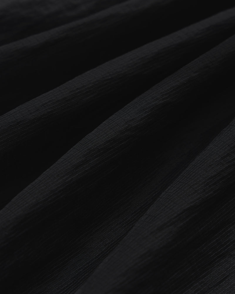 Close-up of black Nylon Track Jacket fabric with soft, diagonal folds creating shadows and depth.