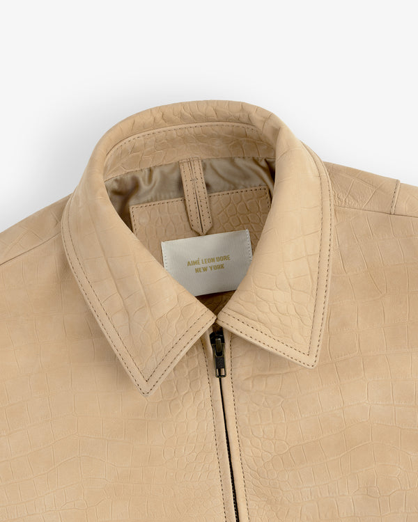 Close-up of a beige Croc-Embossed Nubuck Bomber Jacket with collar and zipper, label reads AIME LEON DORE NEW YORK.