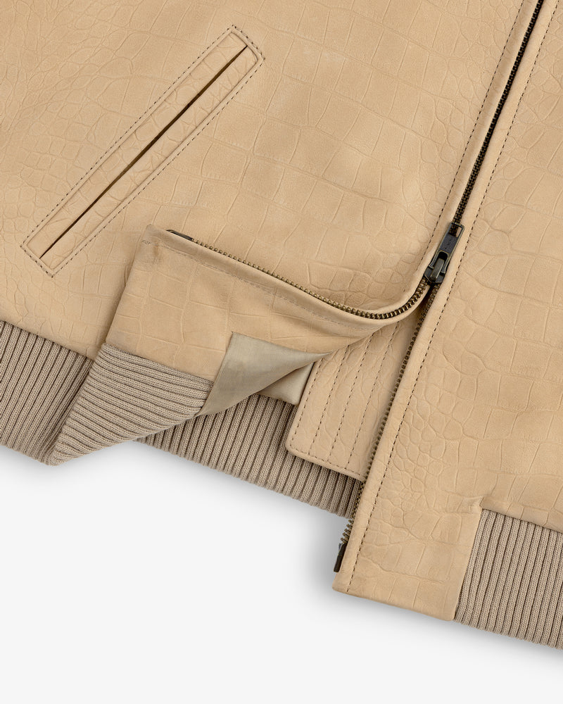 Close-up of the Croc-Embossed Nubuck Bomber Jacket, tan with zipper, pocket, and inner lining partially visible.