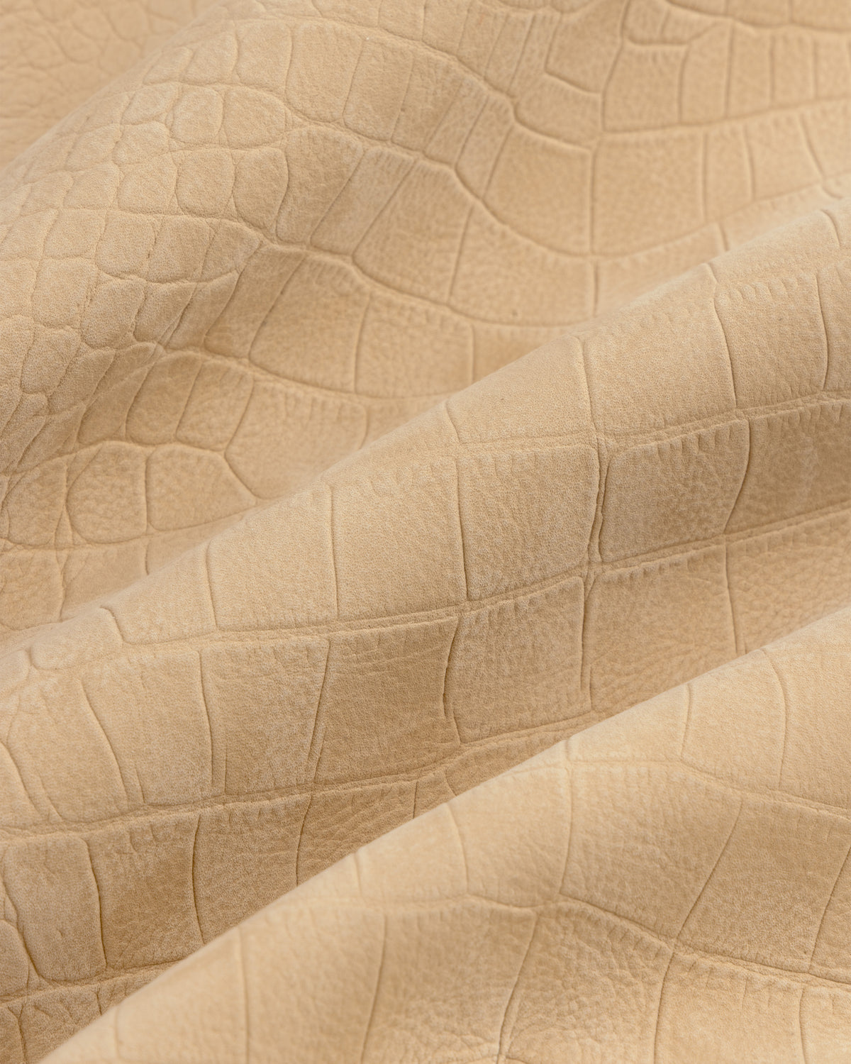Close-up of Croc-Embossed Nubuck Bomber Jacket’s beige, matte, crocodile-patterned textured fabric with gentle folds.