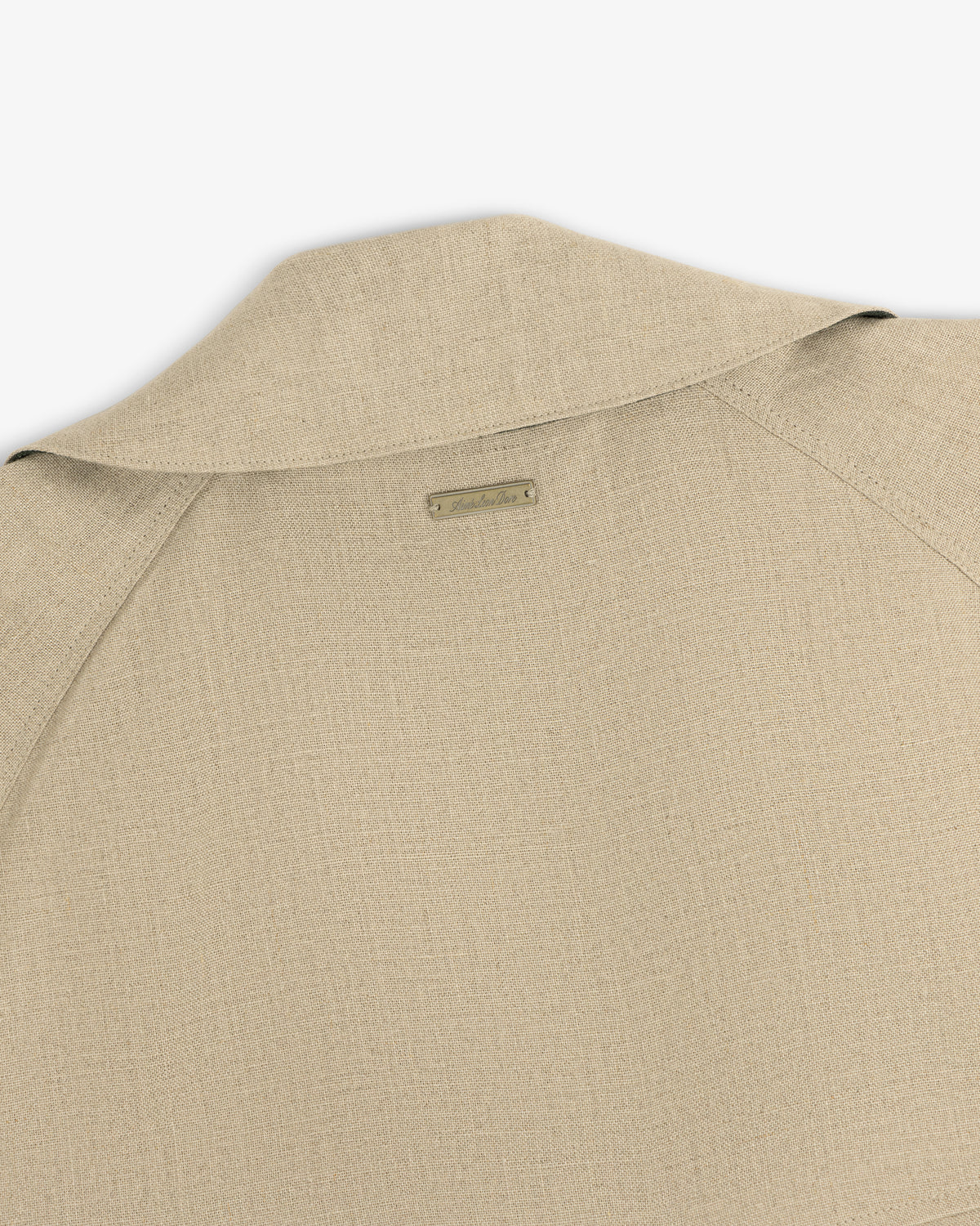 Close-up of the back and collar of the Linen Trench Coat, featuring a small rectangular label at the neck.