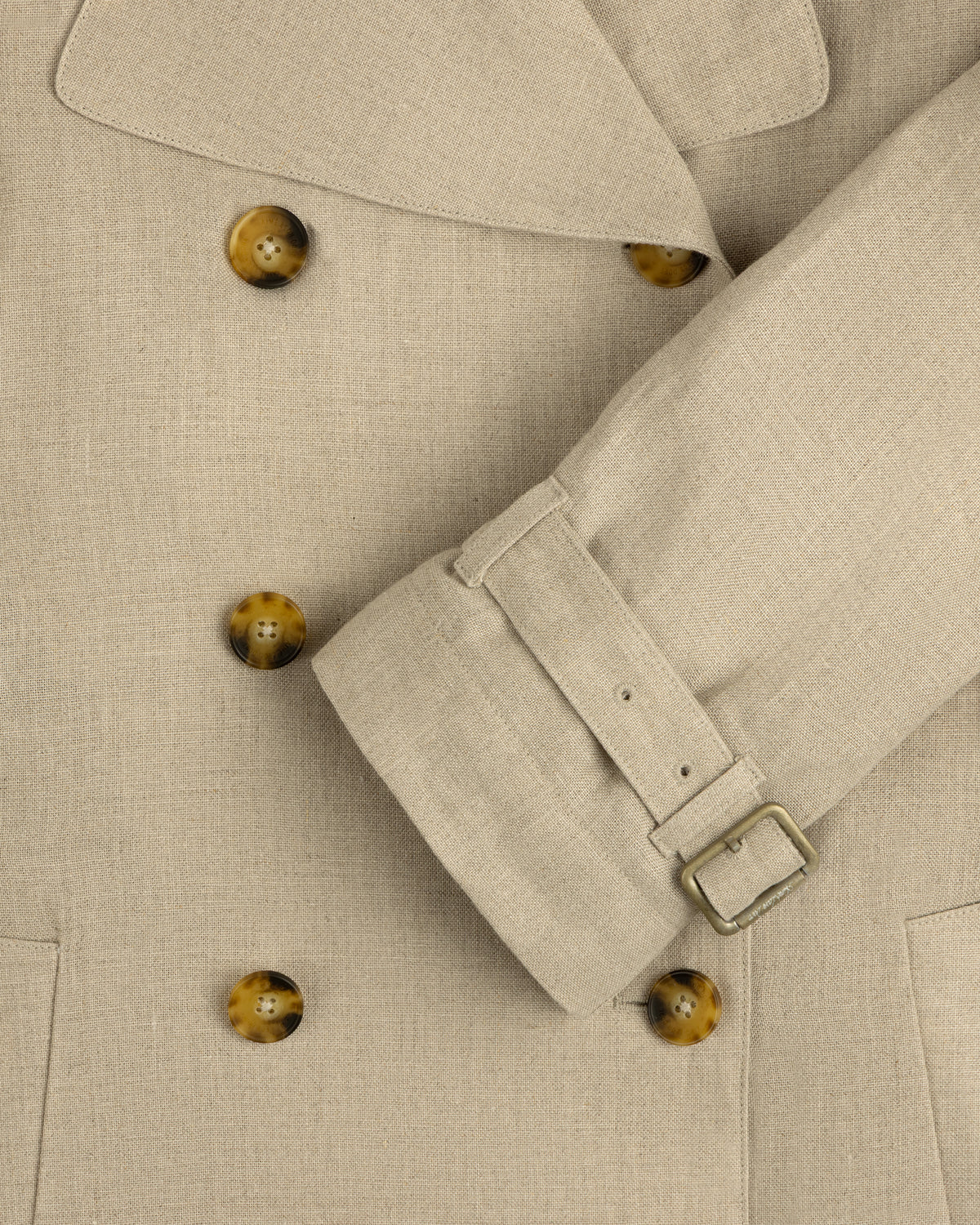 Close-up of the Linen Trench Coat featuring brown buttons and belted sleeve detail.