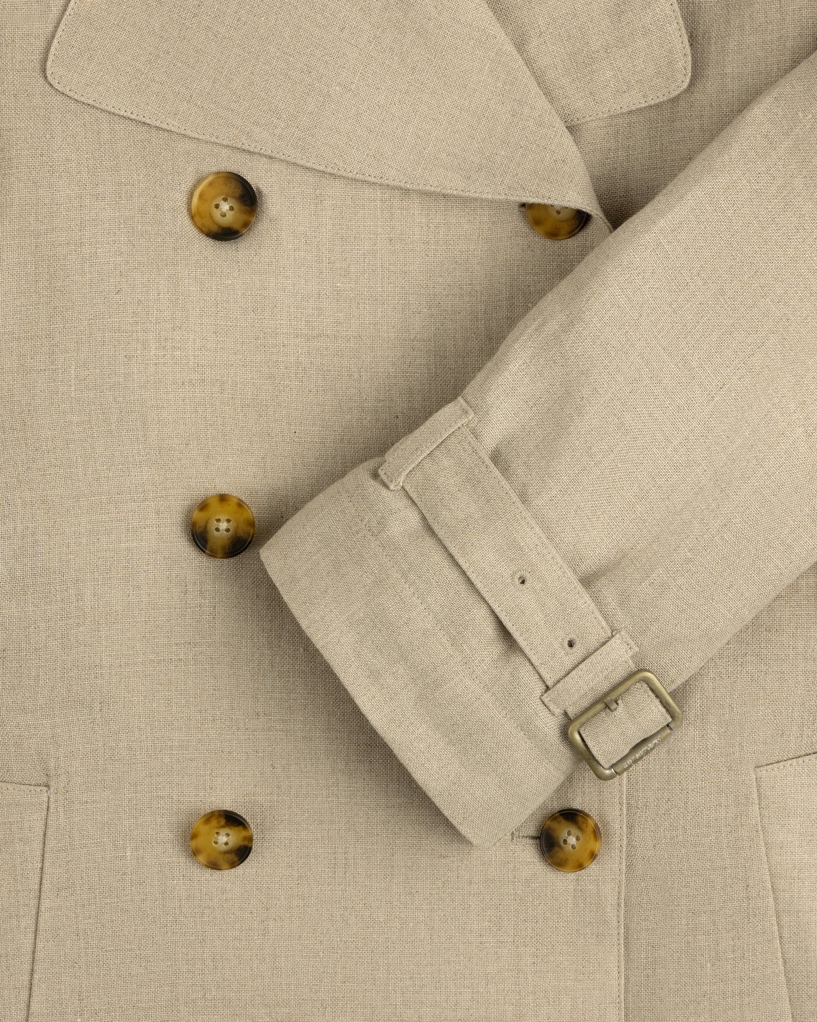 Close-up of the Linen Trench Coat featuring brown buttons and belted sleeve detail.