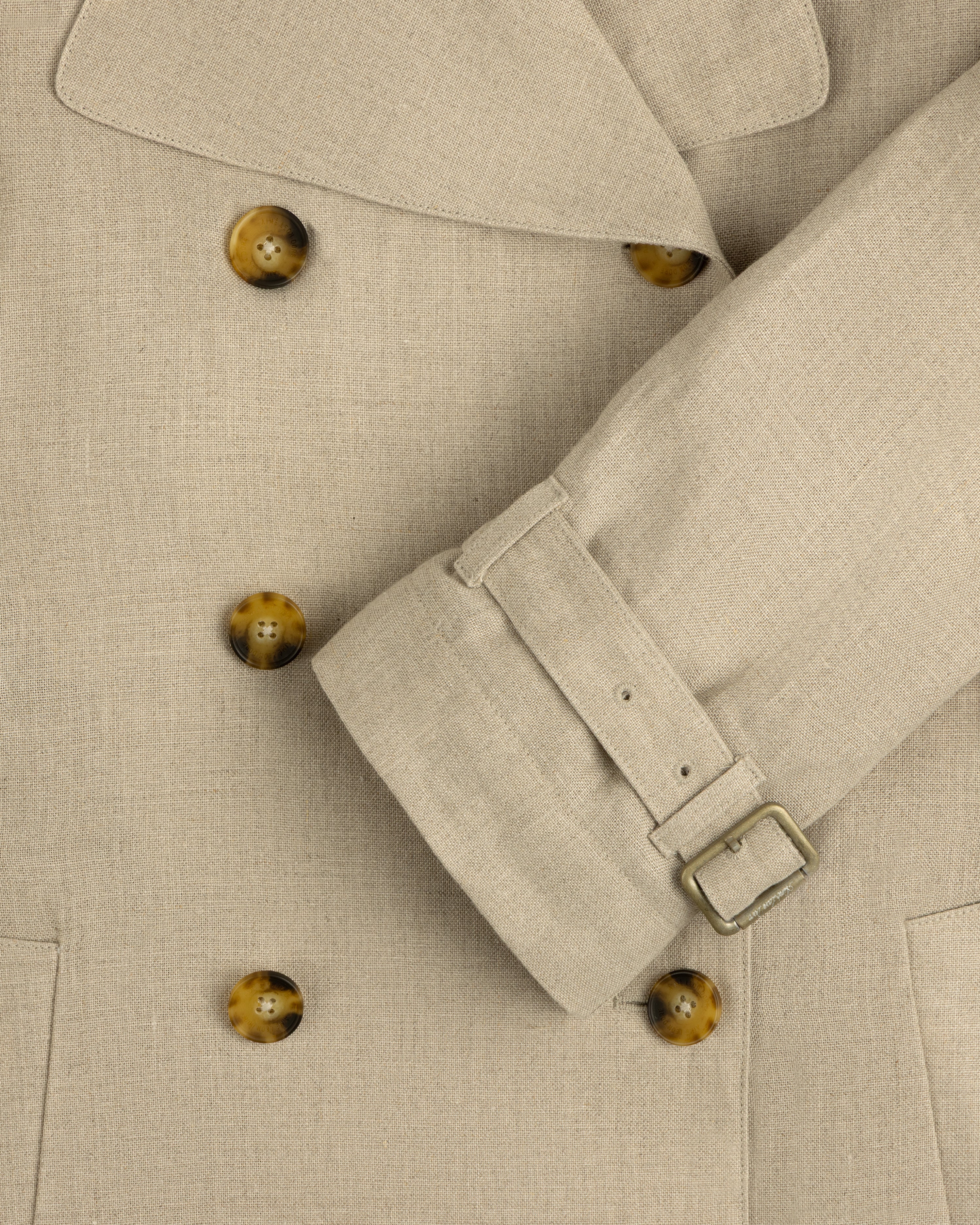 Close-up of the Linen Trench Coat featuring brown buttons and belted sleeve detail.