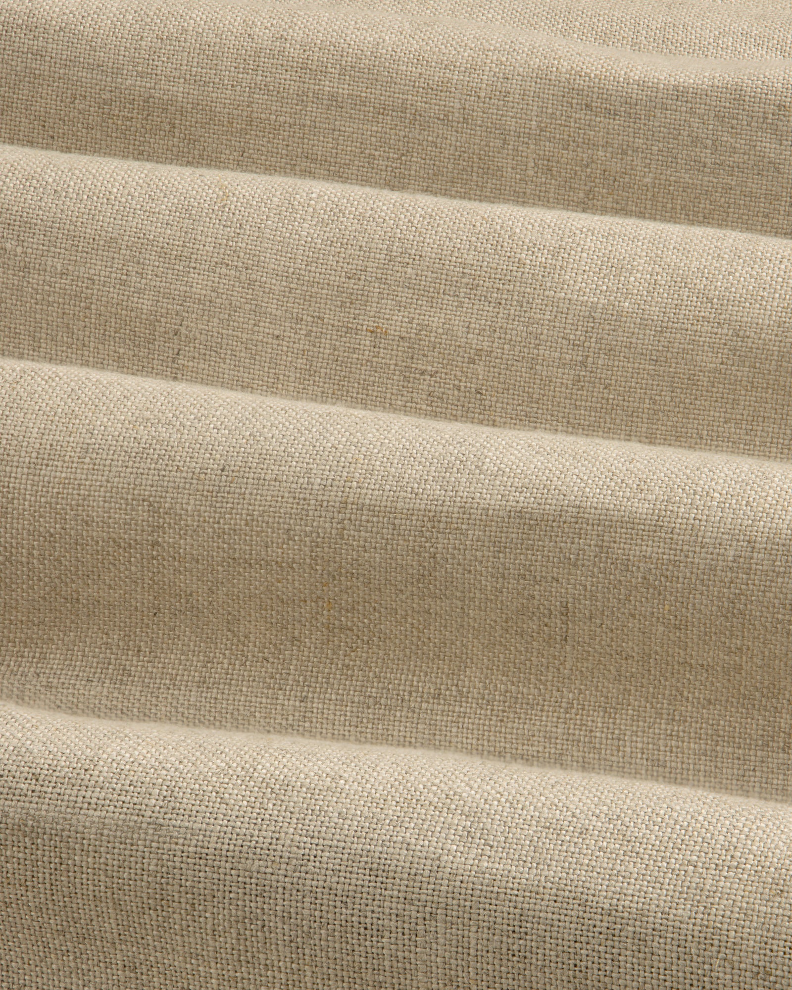 Close-up of beige Linen Trench Coat fabric, showing textured weave and soft, horizontal folds.