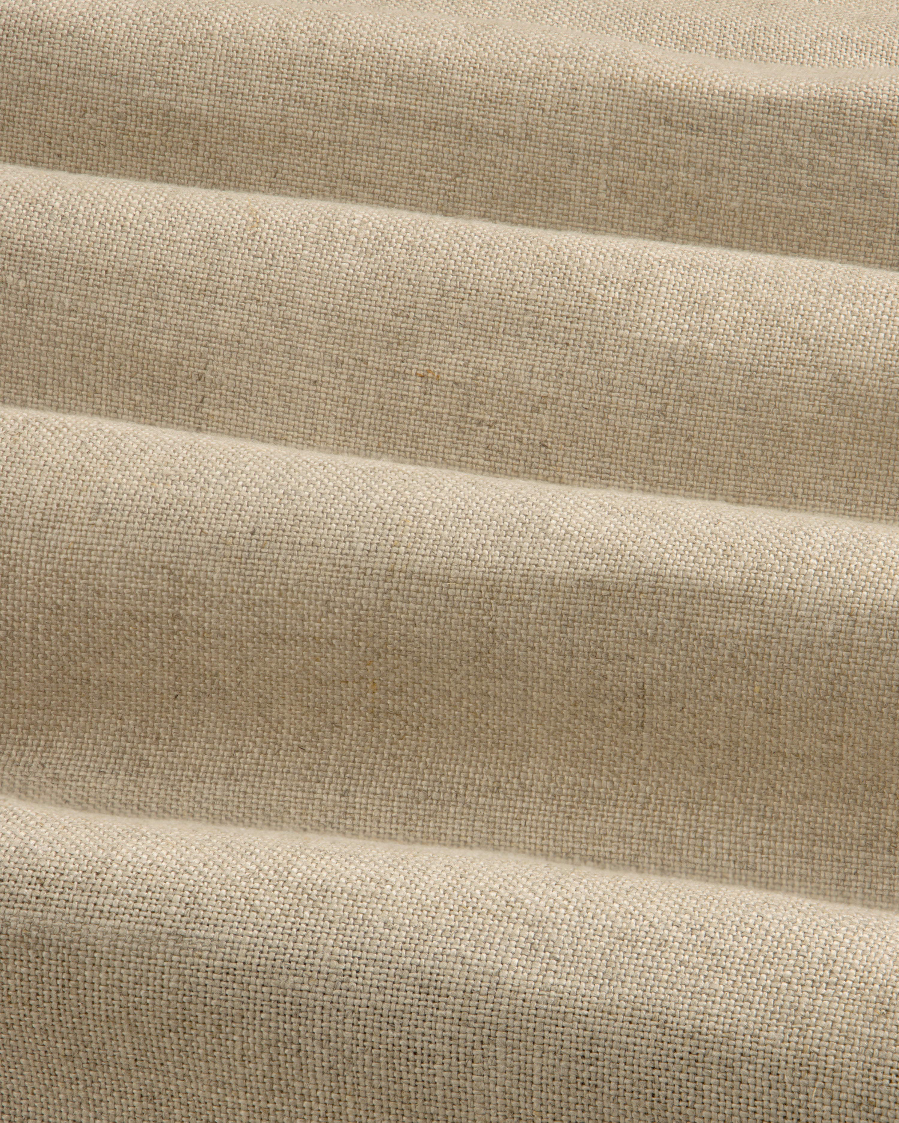 Close-up of beige Linen Trench Coat fabric, showing textured weave and soft, horizontal folds.