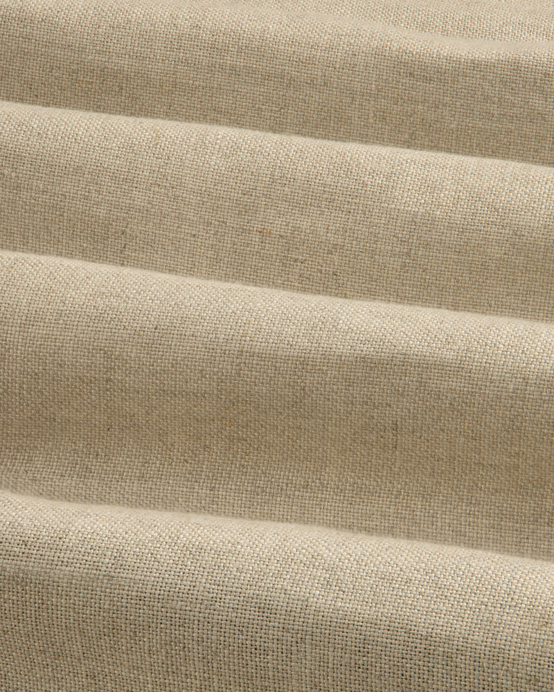 Close-up of beige Linen Trench Coat fabric, showing textured weave and soft, horizontal folds.