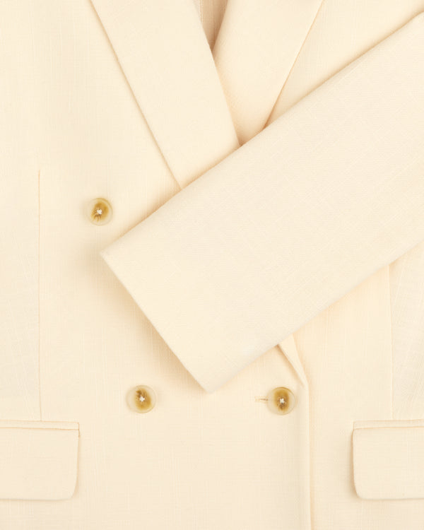 Close-up of the Double-Breasted Unconstructed Blazer in cream with double-breasted buttons and one sleeve folded across.