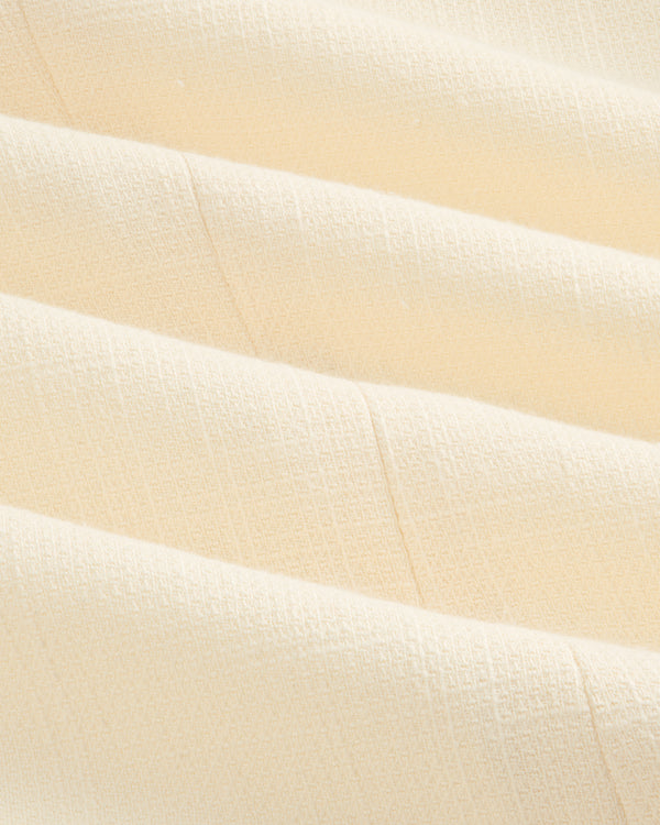 Close-up of cream-colored, textured fabric with soft folds on the Double-Breasted Unconstructed Blazer.