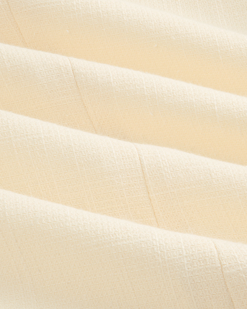 Close-up of cream-colored, textured fabric with soft folds on the Double-Breasted Unconstructed Blazer.