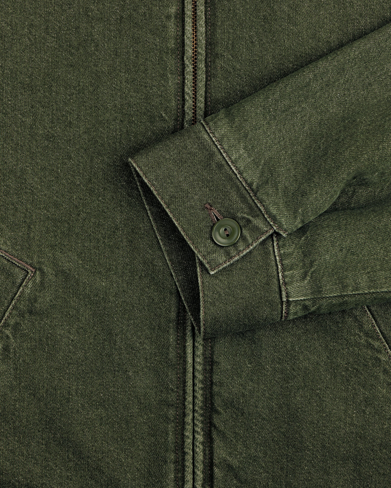 Close-up of a Denim Zip Jacket sleeve with a button cuff and seam details, resting on the jacket front.