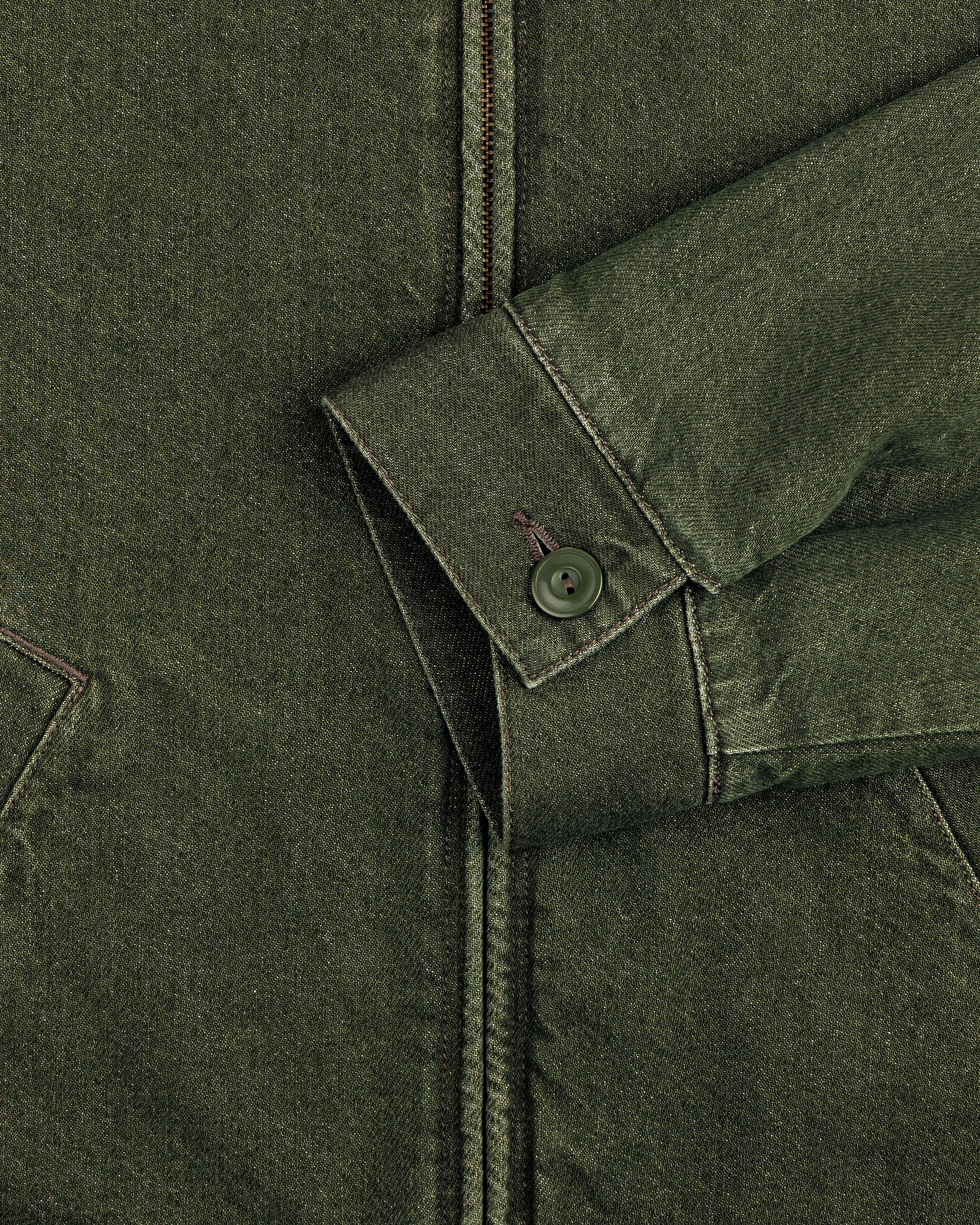 Close-up of a Denim Zip Jacket sleeve with a button cuff and seam details, resting on the jacket front.