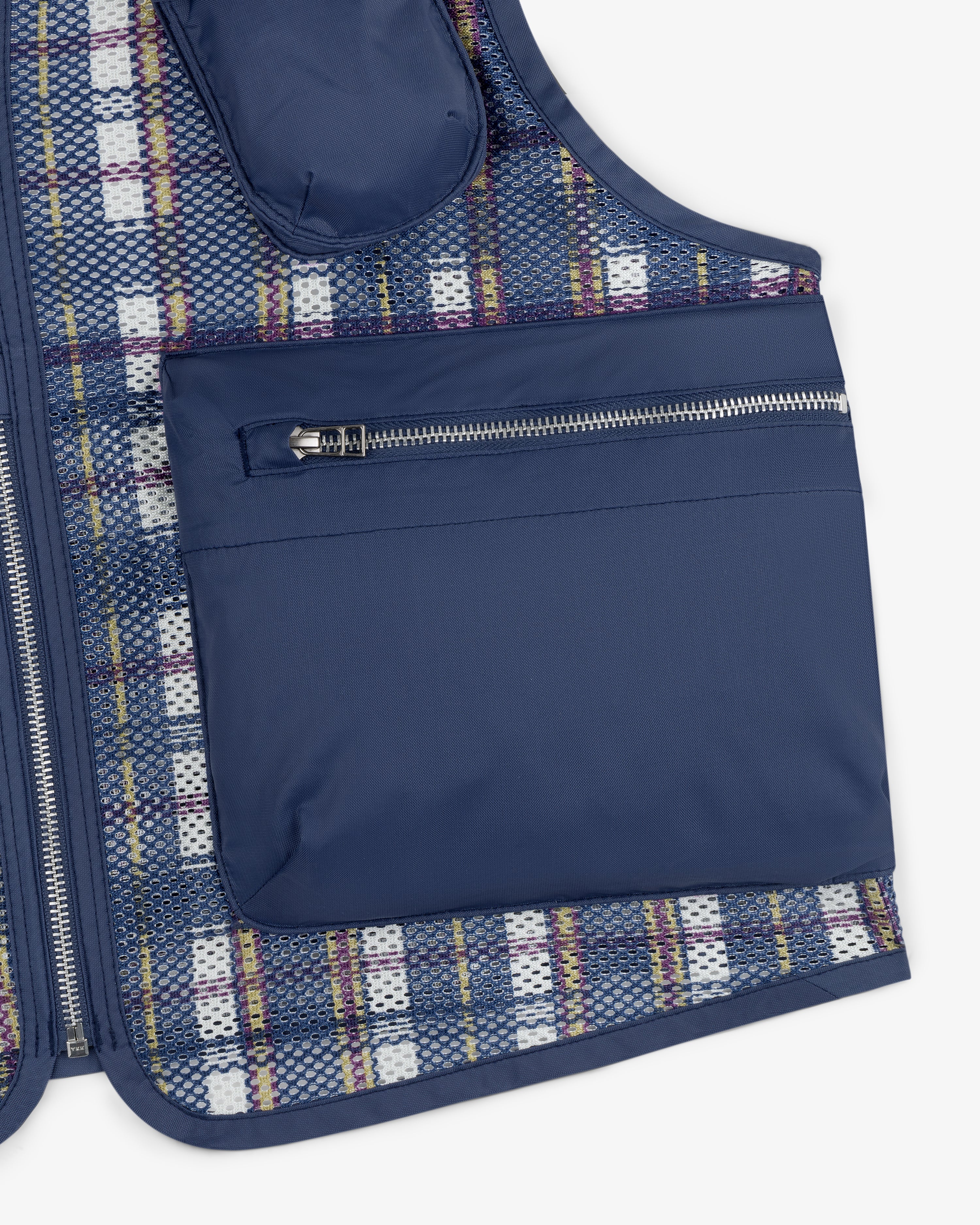 Close-up of the Nylon Madras Utility Vest featuring a large zippered pocket and plaid mesh lining.