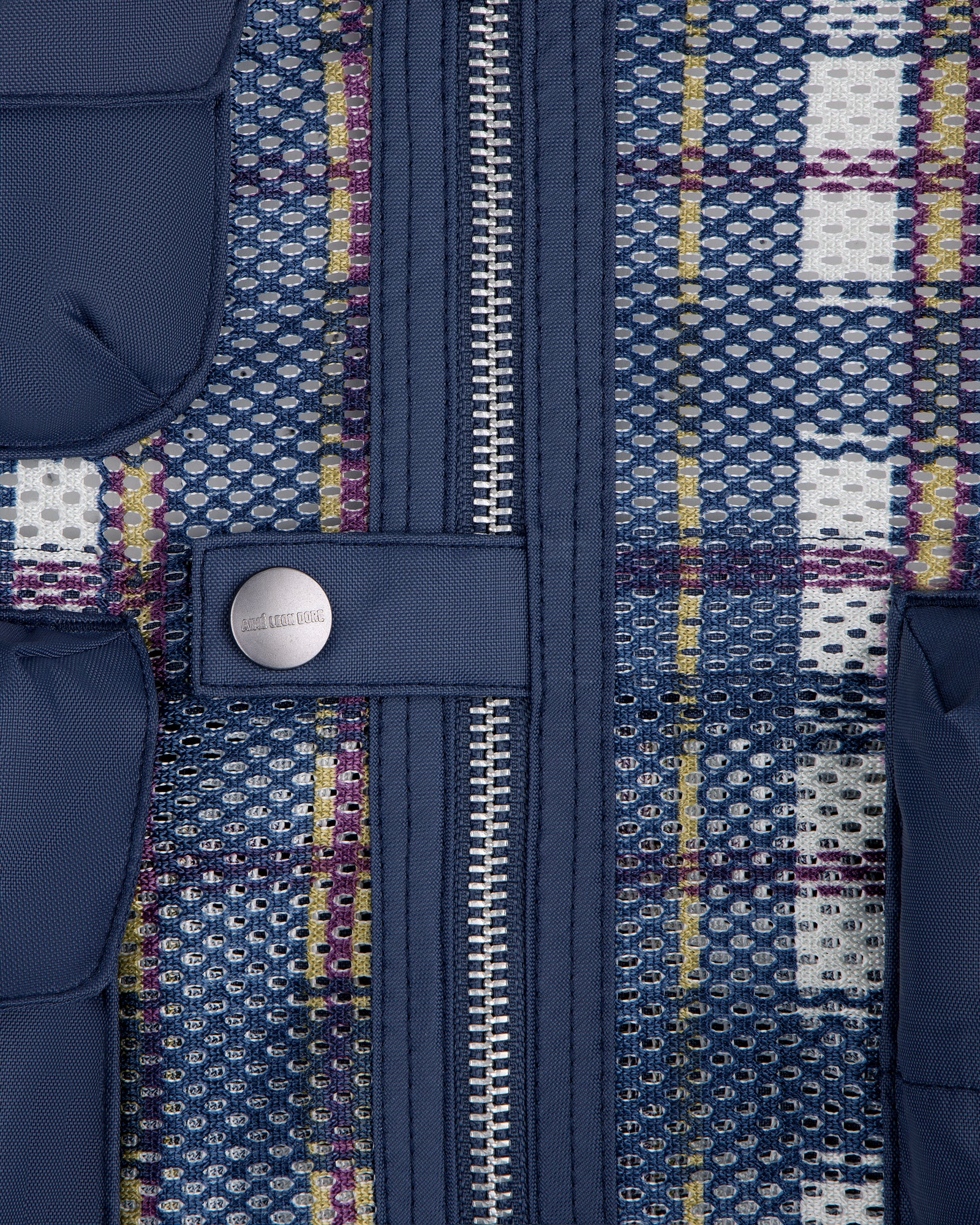 Close-up of the Nylon Madras Utility Vest's blue mesh fabric, zipper, button, pockets, and multicolored threads.