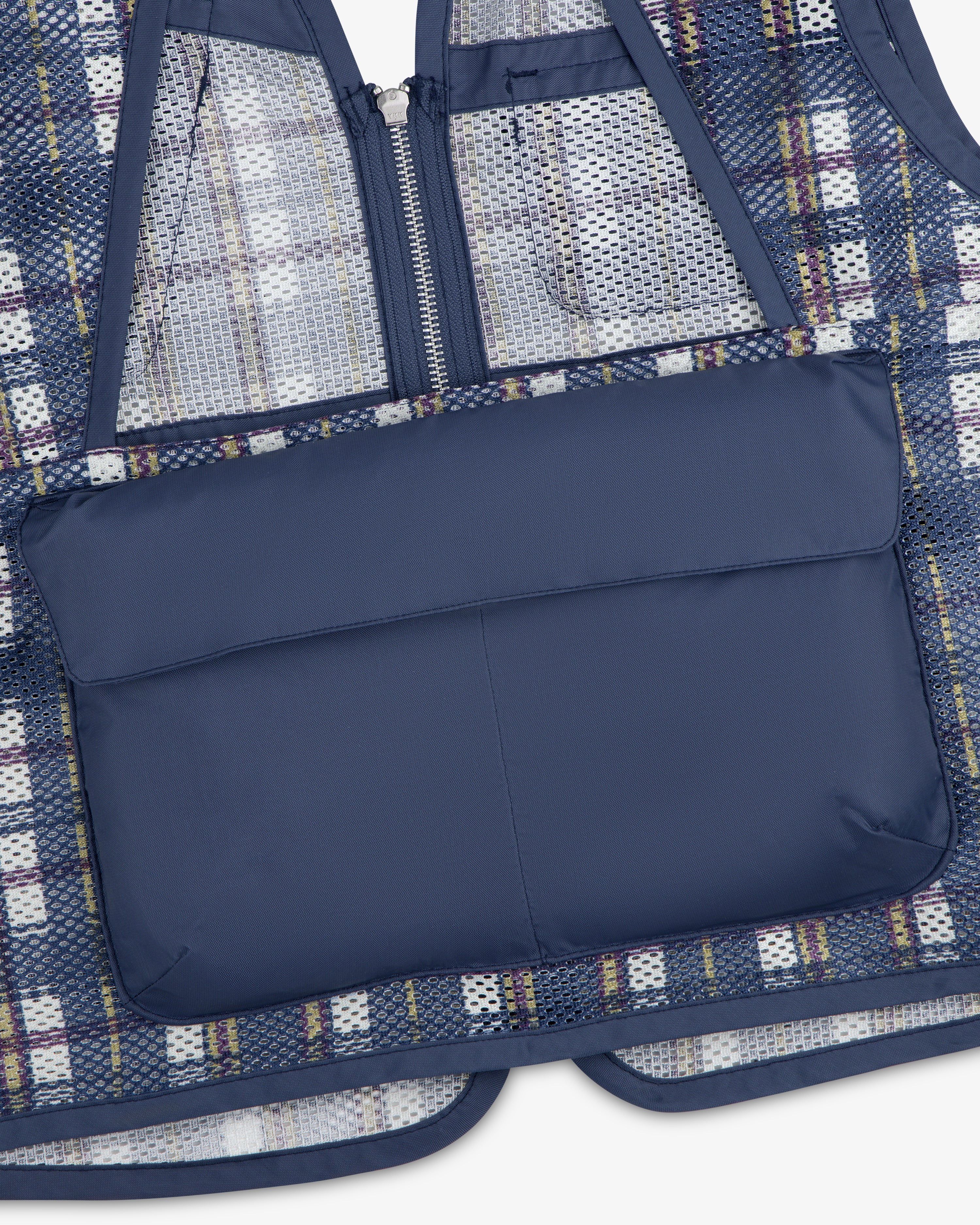 Close-up of the Nylon Madras Utility Vest in blue plaid mesh with a solid navy zippered back pocket.