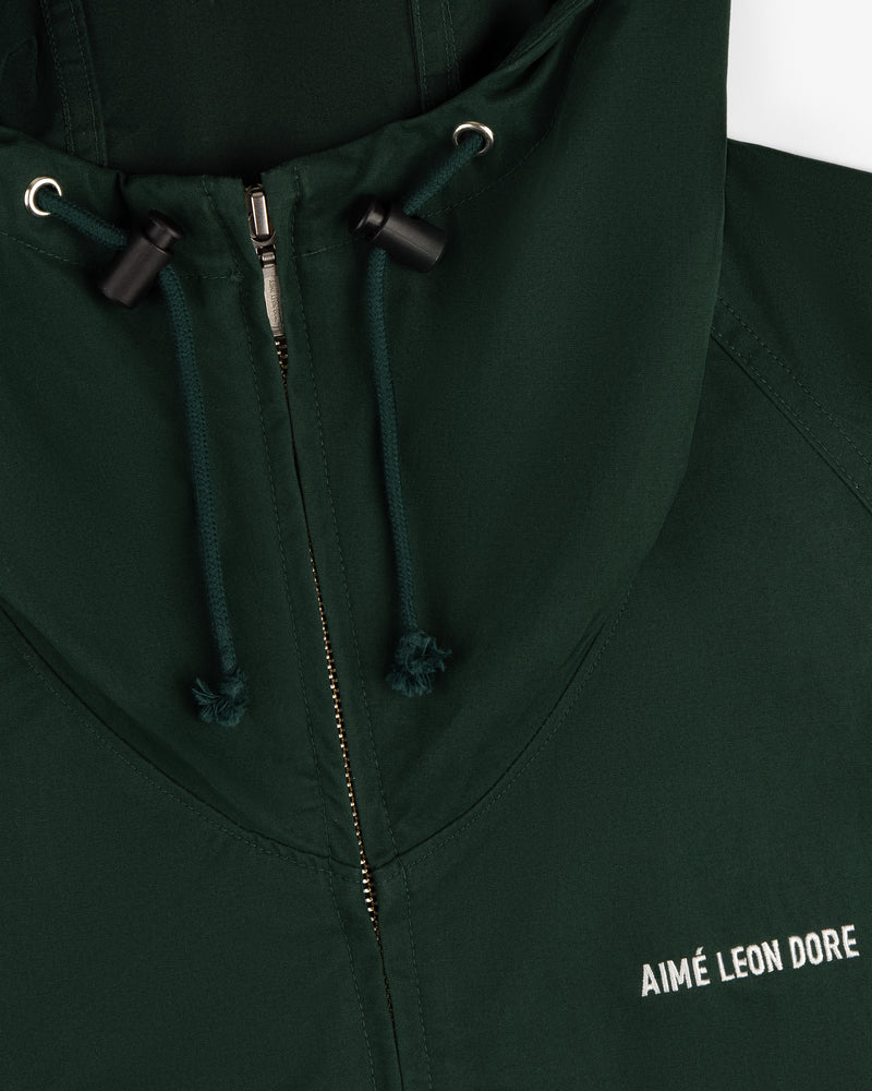 Micro Logo Lightweight Jacket in dark green with zipper, drawstrings, and white AIMÉ LEON DORE chest logo.